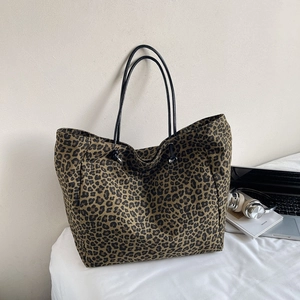 Close-up of leopard print canvas tote bag featuring slender black handles on a desk