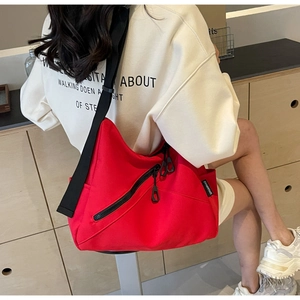 Macro shot of red canvas tote showing diagonal zipper pocket and adjustable strap
