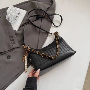 Detailansicht der schwarzen geflochtenen Tasche mit Goldkette und Perlenanhänger-Deko