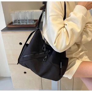 Detail of black nylon hobo bag showing front double zip pockets and adjustable strap