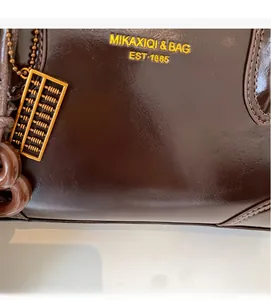 Detail of vintage brown wax leather tote with brand logo and golden abacus charm