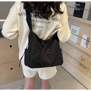 Detail of durable black nylon tote bag with diagonal zipper pocket and adjustable strap