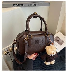 Detail of dark brown leather Boston bag with Mira Mira embossing and teddy bear charm