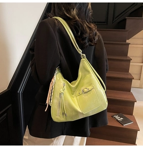 Close-up of light green faux leather hobo bag featuring tassel and metal buckle detail