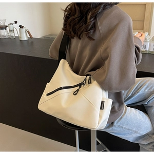 Close-up of off-white casual tote bag showing durable canvas texture and black strap