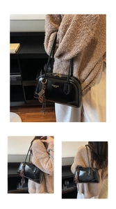 Close-up of black glossy leather tote bag with gold zippers and brand logo printing