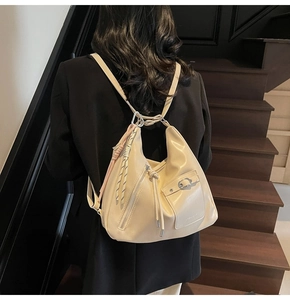 Model view of cream beige hobo bag worn as backpack with woven rope charm details