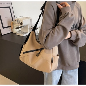 Detail of khaki nylon tote bag showing the side brand label and adjustable black strap