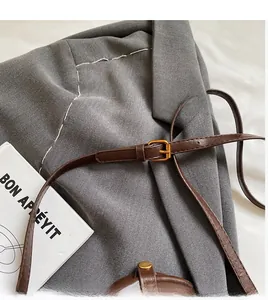 Detail of adjustable dark brown leather shoulder strap with gold metal buckle