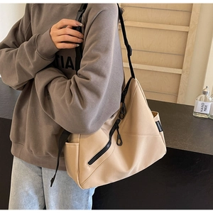 Detail view of khaki canvas tote bag featuring adjustable black strap and side pockets