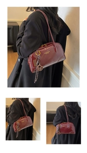 Detail view of burgundy leather bowling bag with gold zipper and unique rope charm