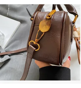 Detail of dark brown leather crossbody bag with pleated texture and gold metal hardware