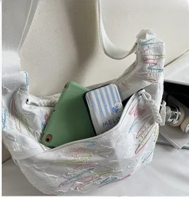 Detailed view of white pleated crescent bag showing spacious interior and colorful stitching