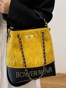 Quilted yellow and black bucket bag with chain strap and metallic stud lettering