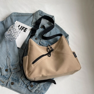 Detail of khaki nylon tote bag with dual diagonal zippers and wide adjustable strap