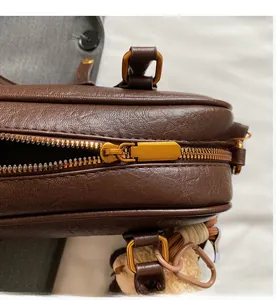 Close-up of smooth bronze metal zipper and vintage hardware on dark brown pebble leather bag