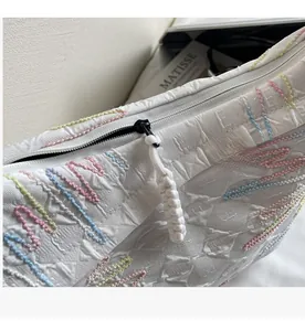 Detailed macro view of smooth black zipper and colorful wavy embroidery on the white bag