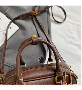 Detail of brown litchi pattern leather handbag with retro gold hardware and handles