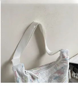 Close-up of colorful wavy embroidery and durable zipper on a white crossbody bag