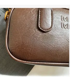 Macro view of dark brown leather texture and embossed MM logo on the shoulder bag