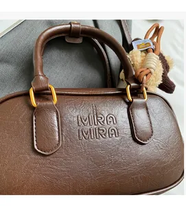 Close-up of brown litchi pattern leather handbag with embossed letters and a bear charm