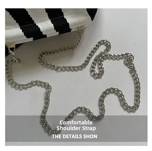 Detail view of black and white striped knitted bag with silver chain strap connection