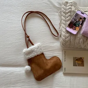 Détail d'un sac à bandoulière en forme de botte de Noël en daim marron avec fausse fourrure