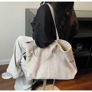 Detail view of large beige suede tote bag showing side buckle and shoulder strap texture