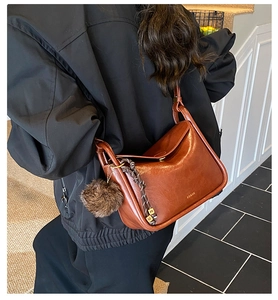 Détail d'un sac vintage en cuir marron avec pompon en peluche et pendentif doré M