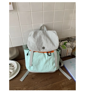 Close-up of contrast color canvas backpack with mint green flap and orange drawstring detail