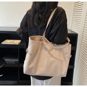 Detail view of the beige suede tote bag featuring side buckle straps and a large interior