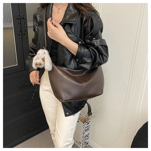Detailed view of dark brown leather tote bag with soft texture and hanging bunny charm