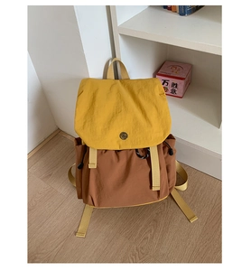 Détail d'un sac à dos d'extérieur bicolore avec rabat jaune et boucle en forme de sourire