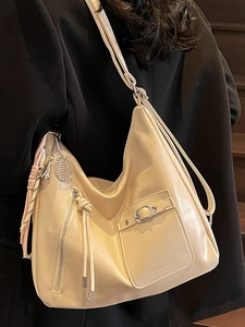 Elegant beige leather shoulder tote bag with metal charms and long tassel decoration