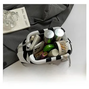 Spacious interior of a black and white checkered knit handbag with chain strap