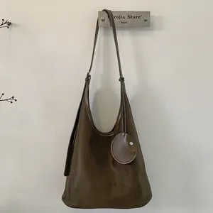 Detail view of dark brown frosted suede shoulder bag with retro circular decorative charm