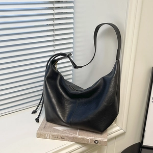 Close-up of black leather tote bag showing soft texture and drawstring knot detail