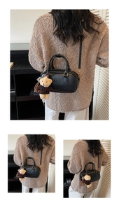 Detail of black leather Boston bag with Mira Mira logo and cute teddy bear charm