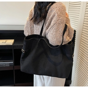Detail of black suede tote bag showing large capacity, matte texture and metal buckle