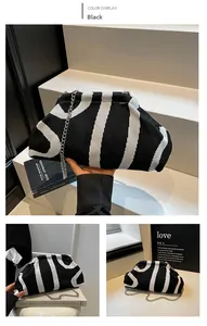Detail of black and white striped knit cloud bag with a silver chain strap and magnetic clasp
