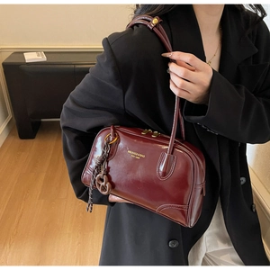 Detailed view of a dark red retro Boston bag with gold hardware and brand lettering