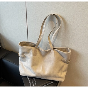 Detailed side view of beige suede tote bag showing the decorative strap buckle and texture