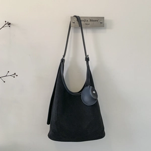 Detail of minimalist black suede hobo bag with adjustable strap and round coin pouch