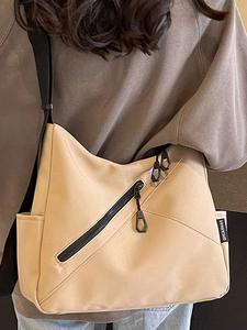 Minimalist beige nylon tote bag with black zip pockets and adjustable strap for women