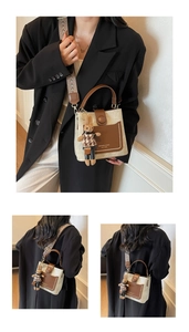 Close-up of beige canvas bucket bag with brown leather pocket and jacquard strap