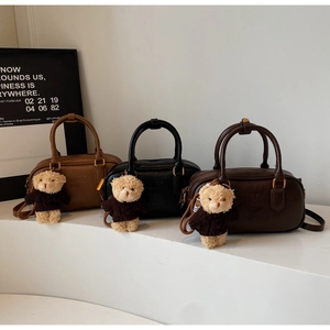 Three MIRA MIRA Boston handbags in tan, black and coffee with cute bear charms on a stand