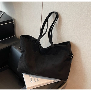 Detail shot of black faux suede tote bag featuring metallic adjustable buckle and strap