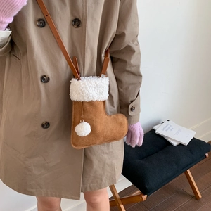 Détail d'un sac bandoulière en forme de botte avec fourrure porté avec un trench kaki