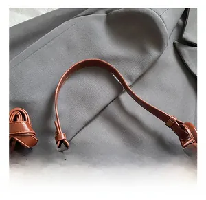 Gros plan sur l'anse du sac en cuir marron avec boucle dorée réglable et coutures