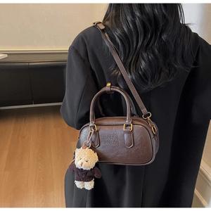 Detail of vintage brown Boston bag with MIRA MIRA embossing and a cute bear charm